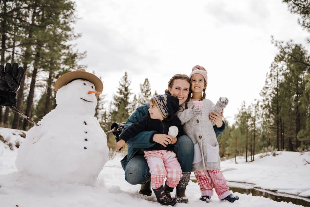 2 girls sitting on white snowman