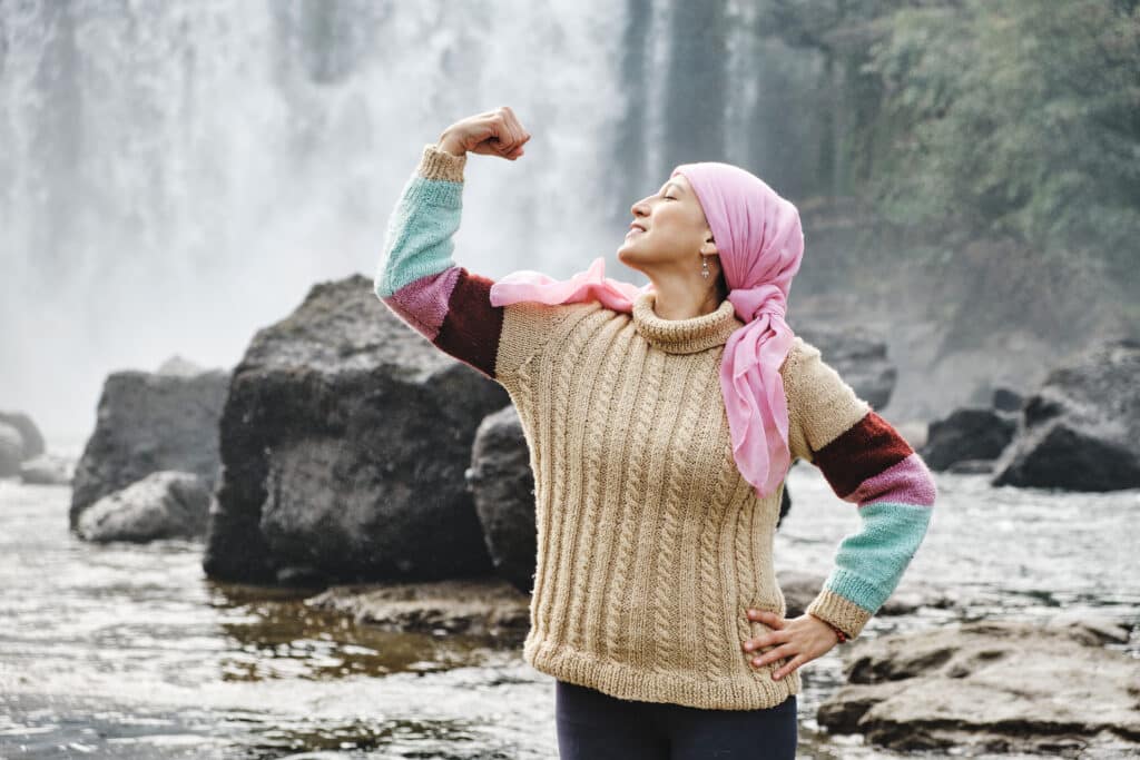 mujer con cáncer mostrando fuerza con los brazos al aire libre